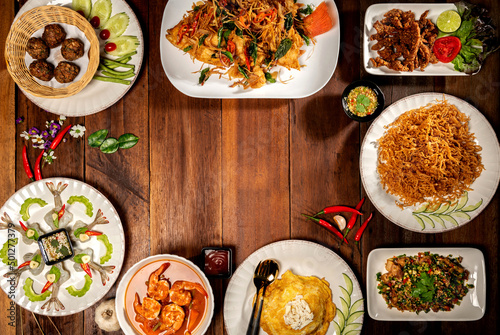 Top view on a delicious variety of Thai Traditional cuisine, Tasty Thai Food Mixed Selections Variety. A Delicious recipe from Asia ingredients on dark wooden table. Restaurant food menu. Copy Space