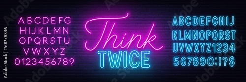Think Twice neon lettering on brick wall background.