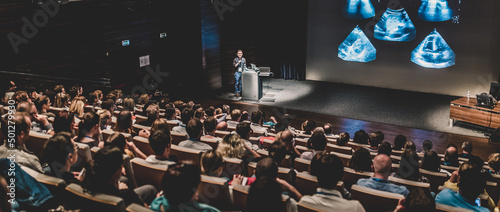 Business speaker giving a talk in conference hall.