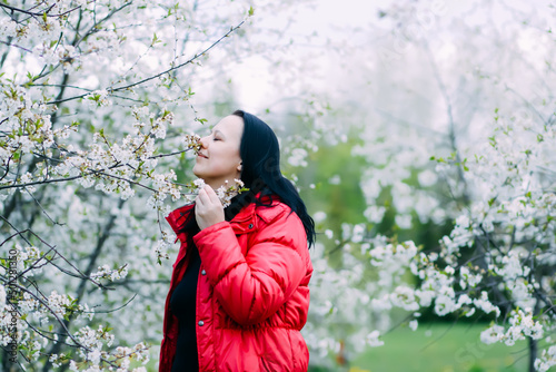 A young woman enjoys spring blossom in a garden. 