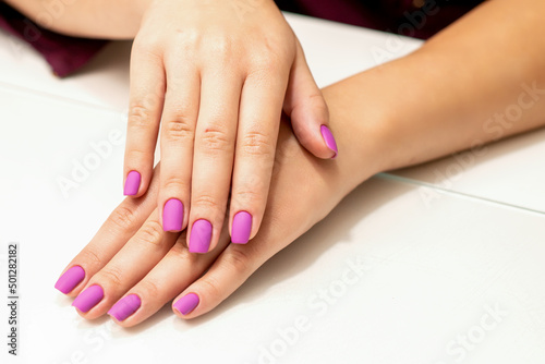 Beautiful manicure with purple  pink nail polish on young caucasian female hands