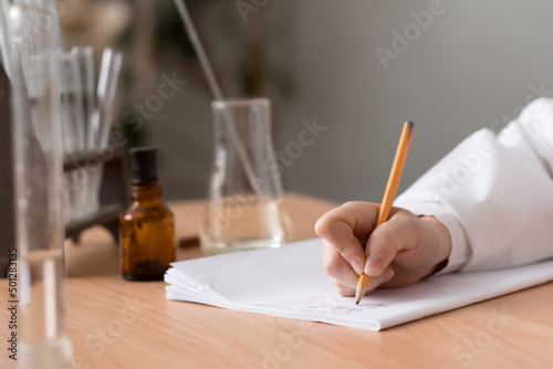hand of woman working in laboratory with samples in tubes and making notes by pensil in workbook photo