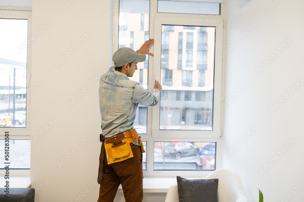 Construction worker installing window in house Construction worker installing window in house