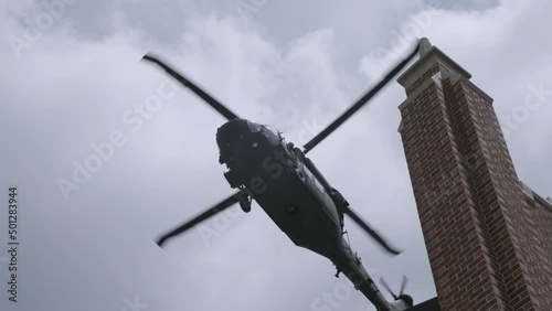 Slow motion shot of blackhawk helicopter flying over a building in the sky. photo