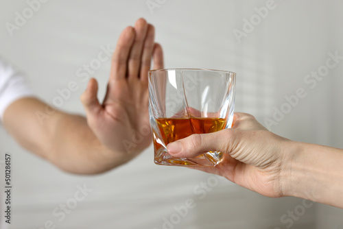 Man refusing to drink whiskey indoors, closeup. Alcohol addiction treatment
