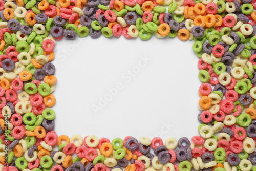 Frame of sweet tasty colorful corn rings on white background, top view. Space for text