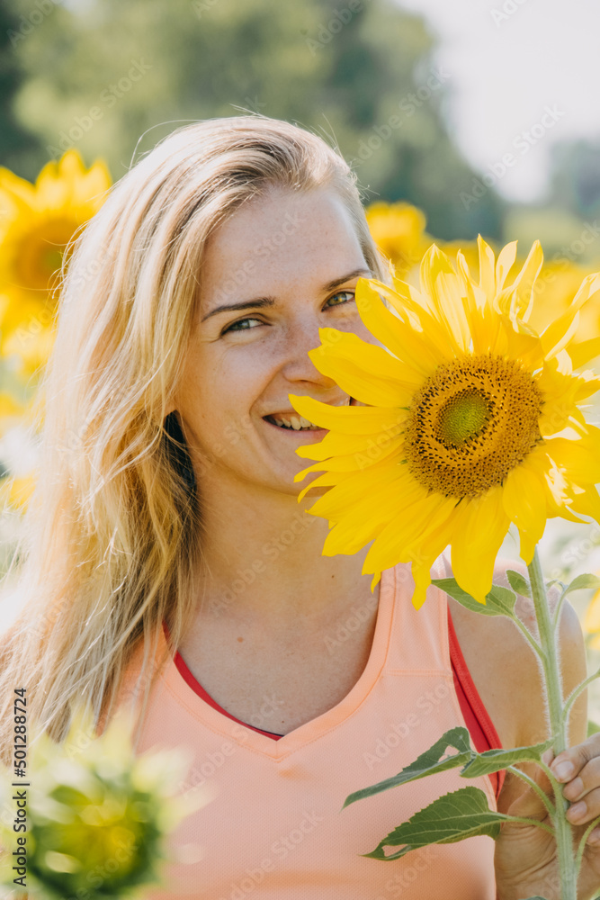 Beautiful young blond woman in a field of sunflowers enjoying of nature and smiling Beautiful young blond woman in a field of sunflowers enjoying of nature and smiling