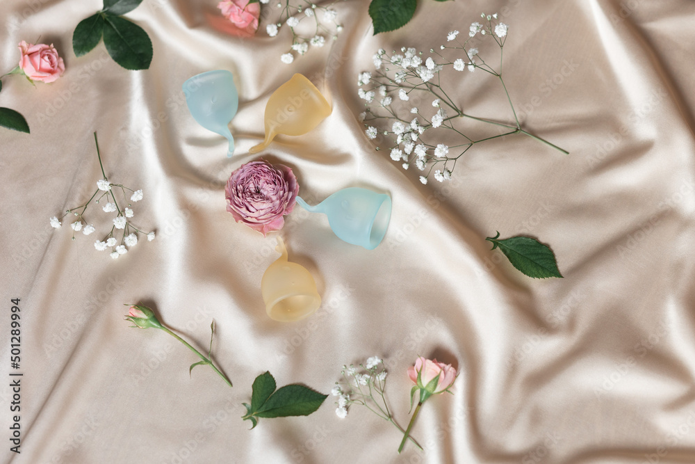 Creative space of menstrual cup on a background of silk and flowers Female and lifestyle. Creative space of menstrual cup on a background of silk and flowers Female and lifestyle.