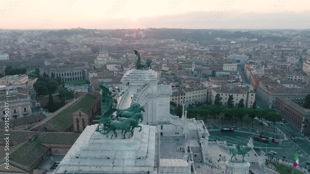 Aerial view of statues on the Victor Emmanuel II National Monument, overlooking the Piazza Venezia, sunset in Rome, Italy - orbit, drone shot