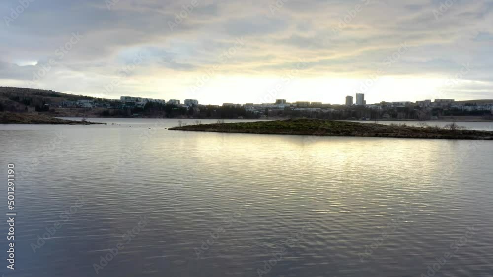 Calm cloudy day flying over the water with a beautiful sunrise close to the city drone footage Calm cloudy day flying over the water with a beautiful sunrise close to the city drone footage