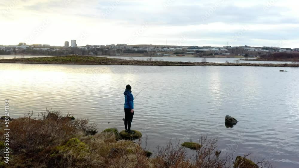 Alone fisherman casting out in the lake close to the city on a calm spring morning Drone footage Alone fisherman casting out in the lake close to the city on a calm spring morning Drone footage