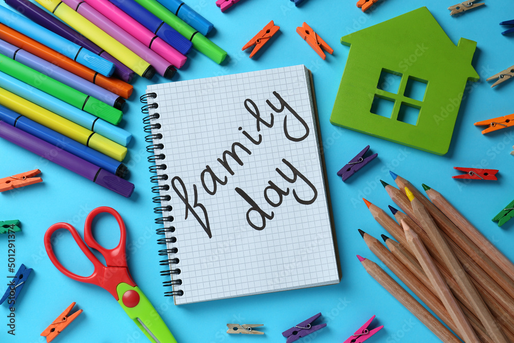 Happy International Family Day. Flat lay composition with notebook and stationery on light blue background Happy International Family Day. Flat lay composition with notebook and stationery on light blue background