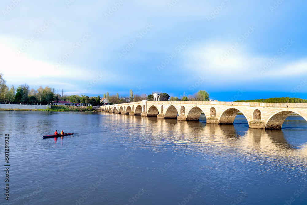 Fototapeta premium Those who canoe in the Meriç river in Edirne. Canoeists passing under the Mecidiye Bridge. Blue sky and peaceful times.