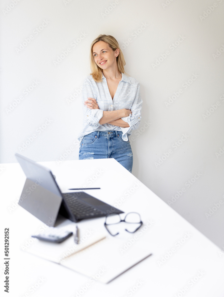 portrait of pretty young blonde business woman standing by her ergonomic height adjustable work desk in her home office portrait of pretty young blonde business woman standing by her ergonomic height adjustable work desk in her home office