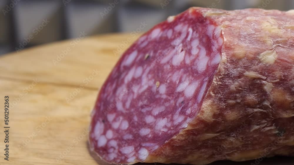 A piece of smoked sausage on a wooden cutting board. Macro video. Half a sausage. A piece of smoked sausage on a wooden cutting board. Macro video. Half a sausage.
