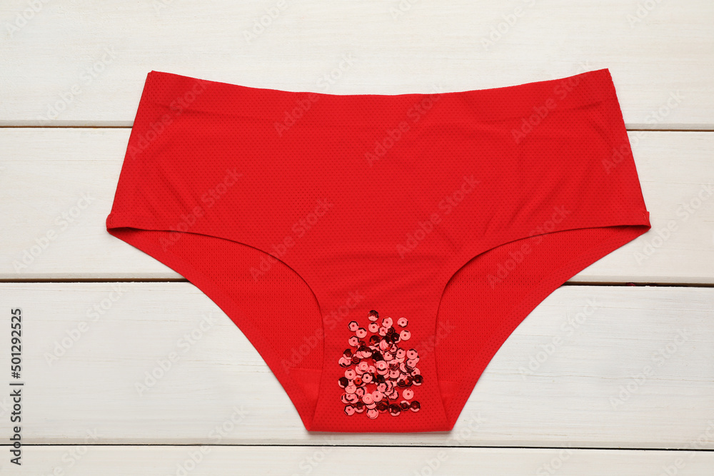 Woman's panties with red sequins on white wooden background, top view. Menstrual cycle