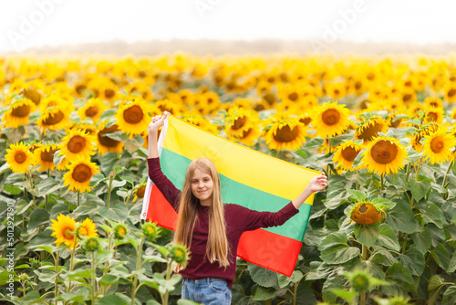 Girl holding flag of Lithuania in a sunflowers field. Lithuanian Flag Day. Independence restoration Day. Travel and love Lithuania concept. Selective focus.