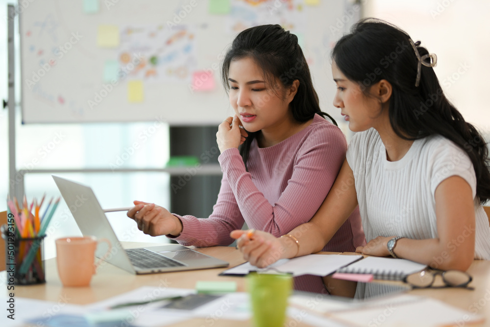 Two female college students doing homework in the co-working space Two female college students doing homework in the co-working space