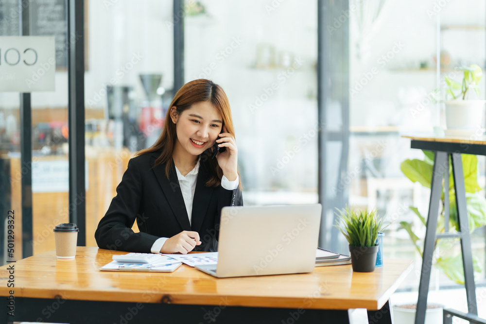 Asian woman in casual clothes is happy and cheerful while communicating with her smartphone and working in a modern office.