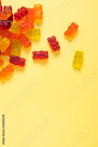 Colored jelly bears on an yellow background with copy space. Top view