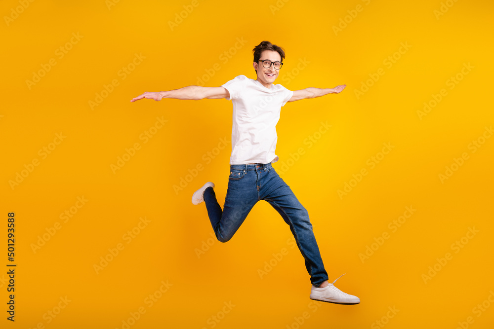 Full length photo of young guy hands wings good mood fly air jump isolated over yellow color background