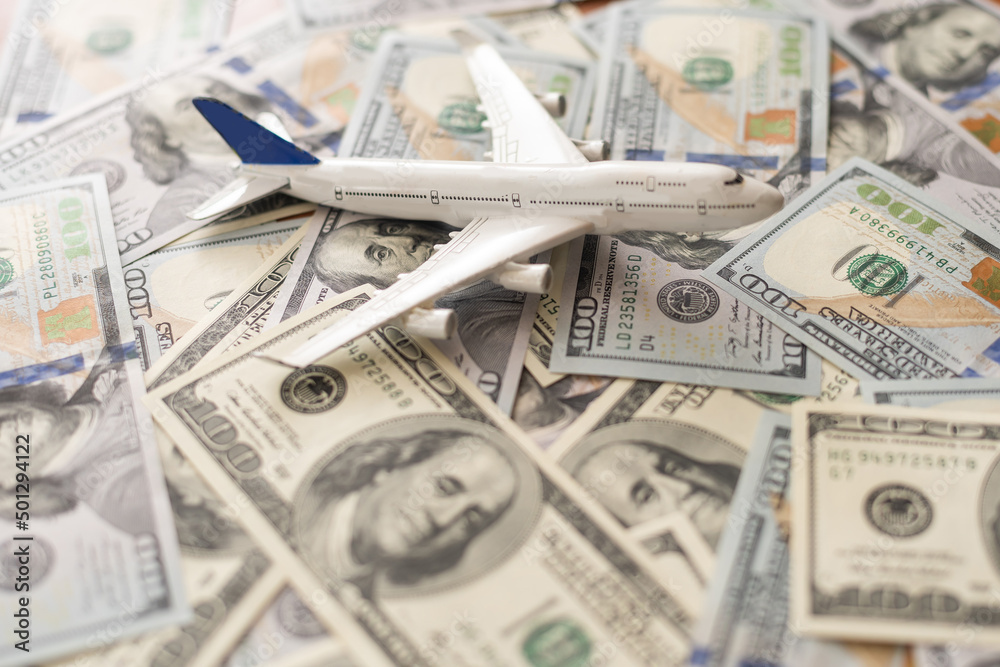 Background of one hundred dollar bills with model airplane on flat lay design to travel concept. Background of one hundred dollar bills with model airplane on flat lay design to travel concept.