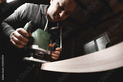 Carpenter with hand electric router machine at work photo
