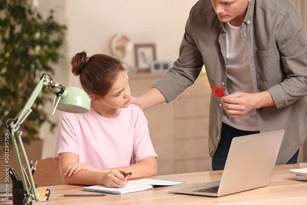 Father Talking With His Teenage Daughter About Contraception While She Doing Homework At Home 