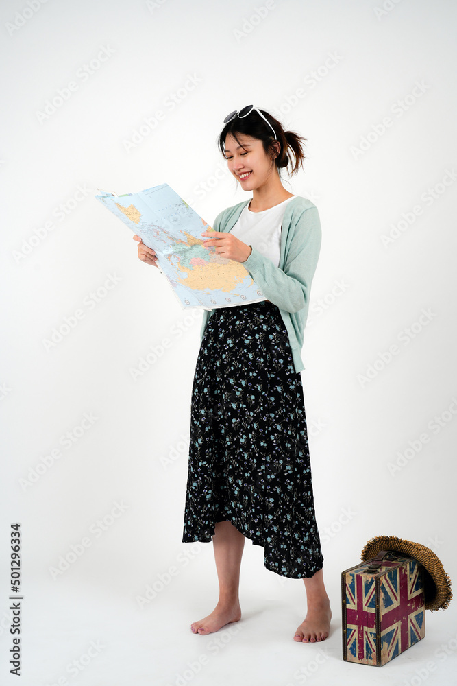 Positive smiling young asian female tourist searches for inspiring places, holds paper map, finds new sightseeing for discovering, wears round spectacles, isolated on white studio wall Positive smiling young asian female tourist searches for inspiring places, holds paper map, finds new sightseeing for discovering, wears round spectacles, isolated on white studio wall