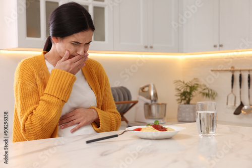 Photography Young woman feeling nausea while seeing food at table in kitchen