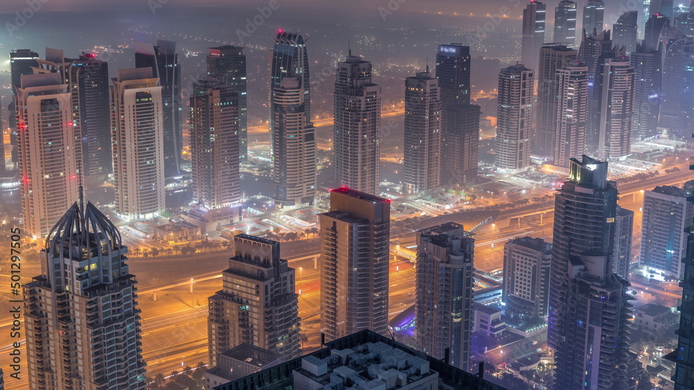 JLT skyscrapers and marina towers near Sheikh Zayed Road aerial night to day timelapse. Residential buildings