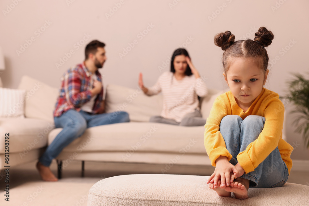 Sad little girl and her arguing parents on sofa in living room Sad little girl and her arguing parents on sofa in living room