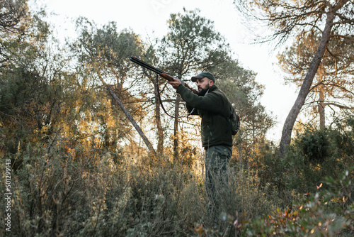 Young hunter aiming with his shotgun in nature © Jordi Mora