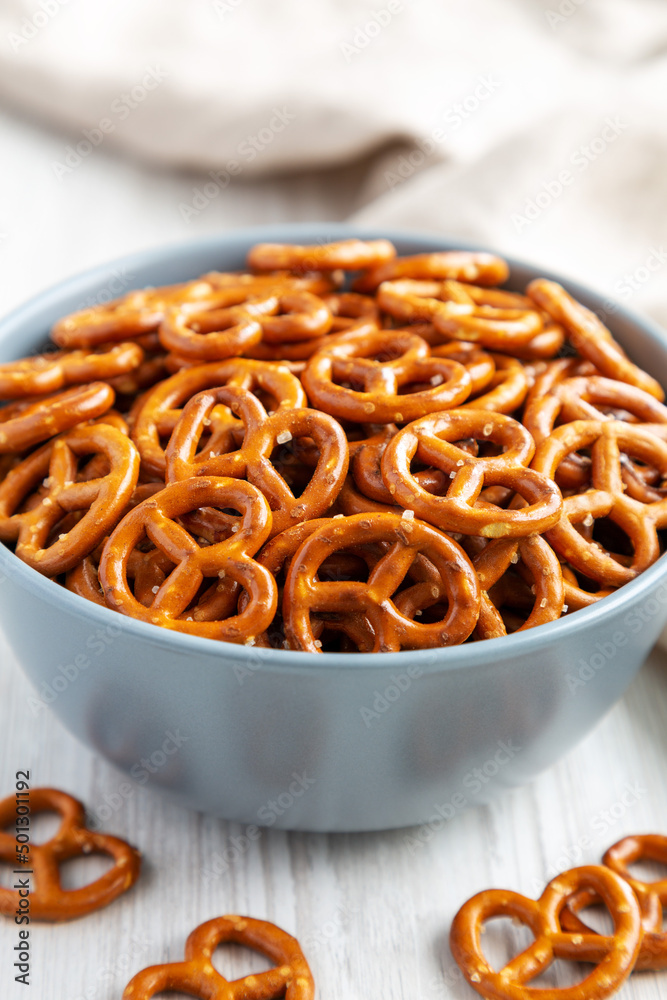 Crispy Salty Baked Pretzels in a Bowl on a white wooden background, side view. Close-up. Crispy Salty Baked Pretzels in a Bowl on a white wooden background, side view. Close-up.
