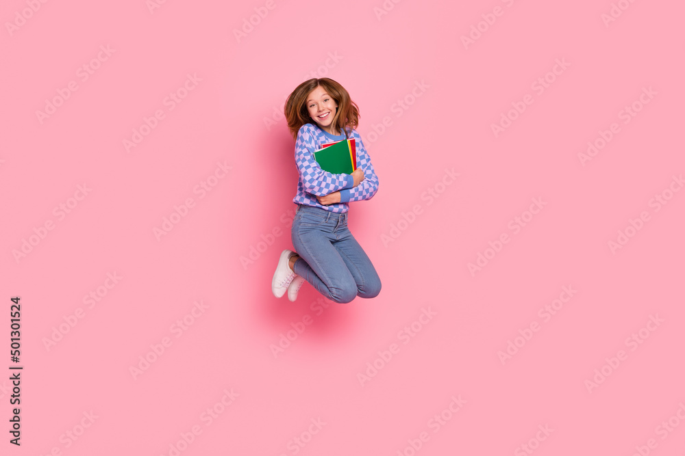 Full size photo of blond small girl jump hold book wear sweater jeans sneakers isolated on pink background Full size photo of blond small girl jump hold book wear sweater jeans sneakers isolated on pink background