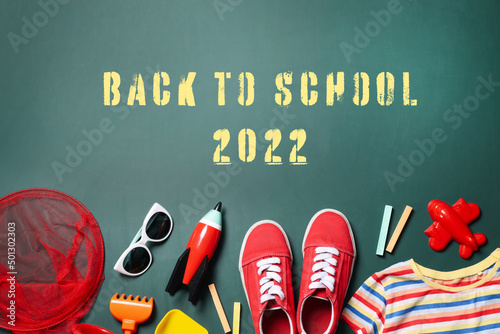 Back to school 2022. Different child accessories on green chalkboard, flat lay photo