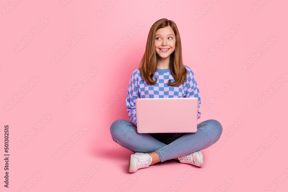 Full length photo of young girl sit floor use laptop dream idea look empty space isolated over pink color background Full length photo of young girl sit floor use laptop dream idea look empty space isolated over pink color background
