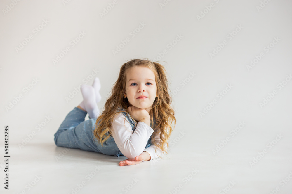 beautiful cute baby girl lies on her stomach and looks into the camera with slightly wavy hair. pretty Baby. happy childhood. beautiful cute baby girl lies on her stomach and looks into the camera with slightly wavy hair. pretty Baby. happy childhood.