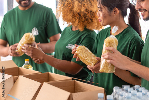 charity, donation and volunteering concept - close up of international group of happy smiling volunteers packing food in boxes at distribution or refugee assistance center
