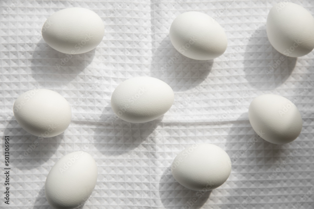 Eight white chicken eggs on a white waffle towel with texture. Kitchen still life, cooking concept, sun light Eight white chicken eggs on a white waffle towel with texture. Kitchen still life, cooking concept, sun light
