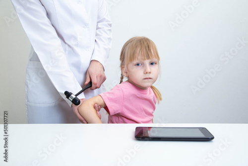 Doctor neurologist checks triceps reflex in a girl age 5 years patient. Examination by a neurologist in the office, medical, nervous system. Copy space for text photo