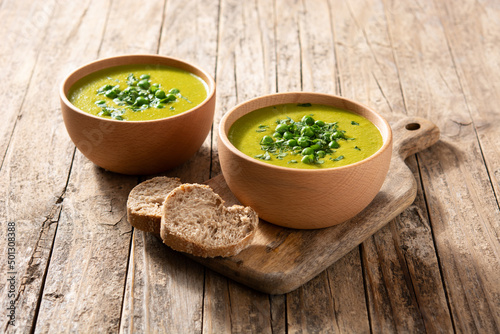 Green pea soup in a wooden bowl on rustic wooden table photo