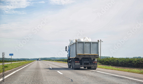 Fotografie, Obraz Transporting waste in a dump truck on the highway for recycling