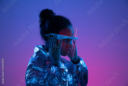 Woman adjusting futuristic smart glasses against multi-colored background photo