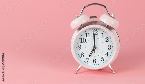 pink vintage alarm clock 7 o'clock on pink background with copy space.
