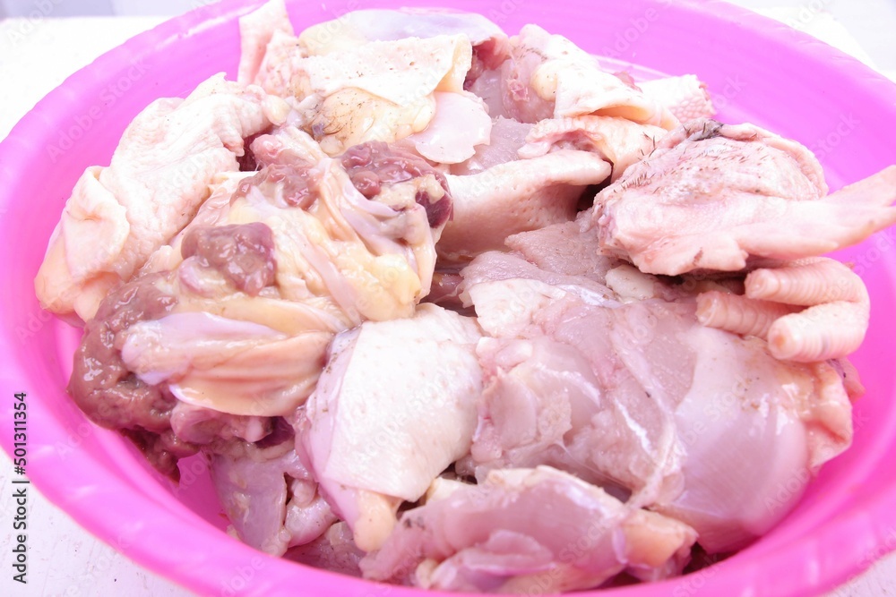 closeup, pile of chicken pieces in a pink bowl. plain white isolated closeup, pile of chicken pieces in a pink bowl. plain white isolated