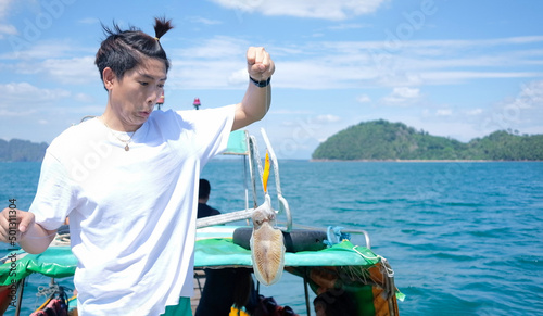 Young asian man surprise of fishing big squid in Pak meng Trang