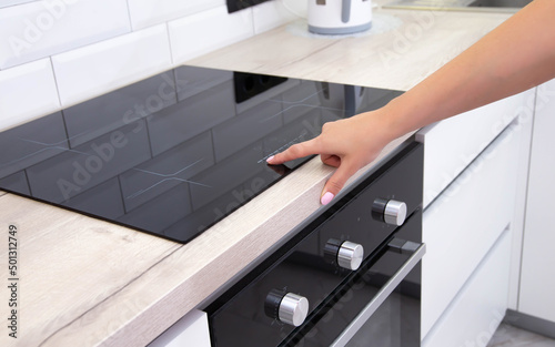 Modern induction hob in the kitchen. A woman's hand sets the heating power of the burner, ceramic photo
