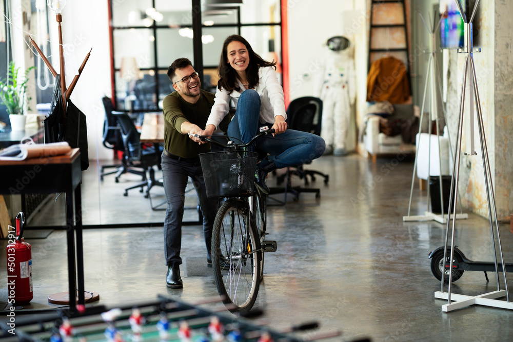 Colleagues in office. Businesswoman and businessman with bicycle. Two friends having fun together Colleagues in office. Businesswoman and businessman with bicycle. Two friends having fun together