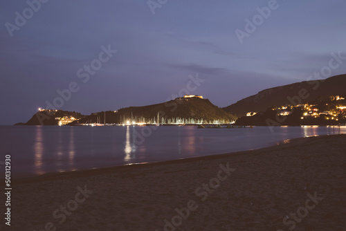 Porto di Cala Galera visto dalla spiaggia della Feniglia. Immagine notturna con barche illuminate. photo